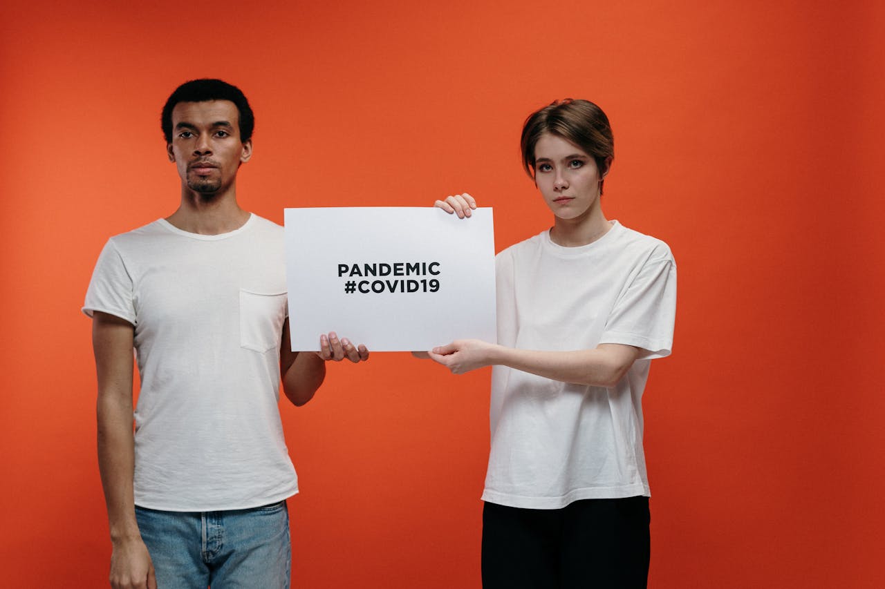 Young adults holding a sign highlighting COVID-19 pandemic awareness.