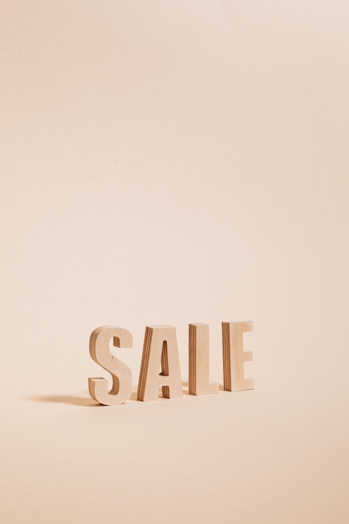 Wooden letters spelling SALE on a neutral beige background, perfect for promotions.