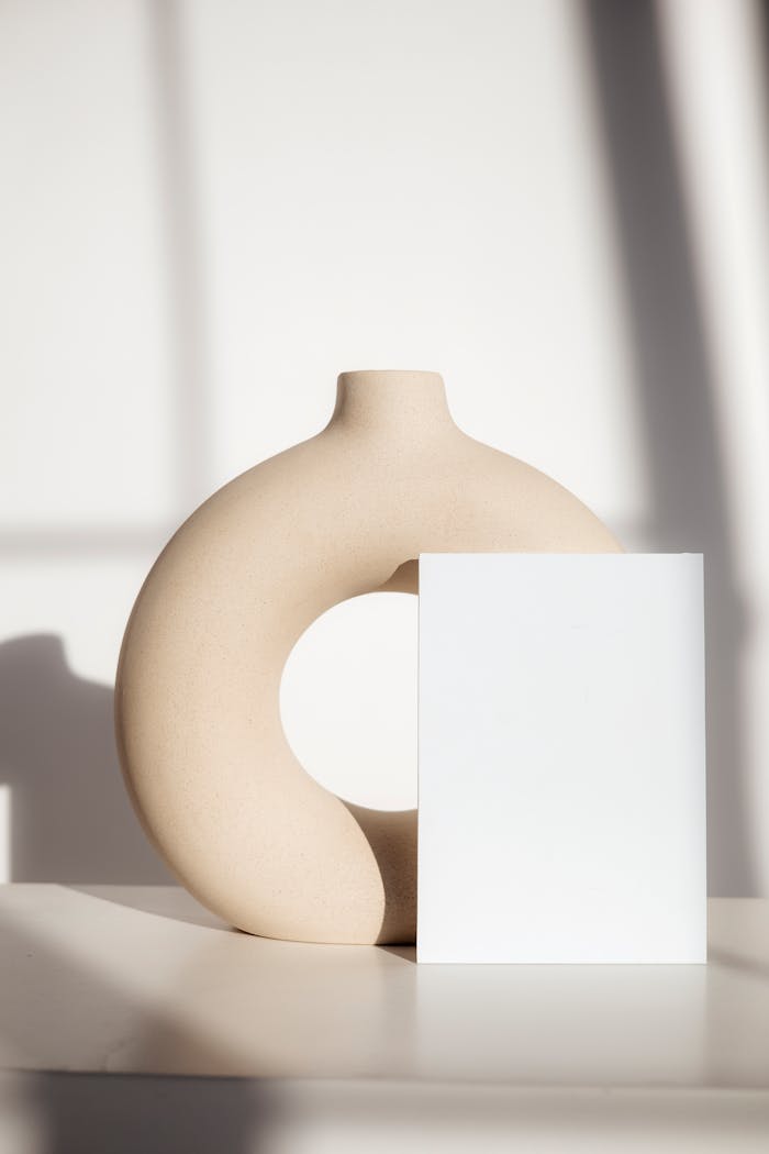 Elegant minimalist setup with a circular vase and blank book for modern styling concepts.